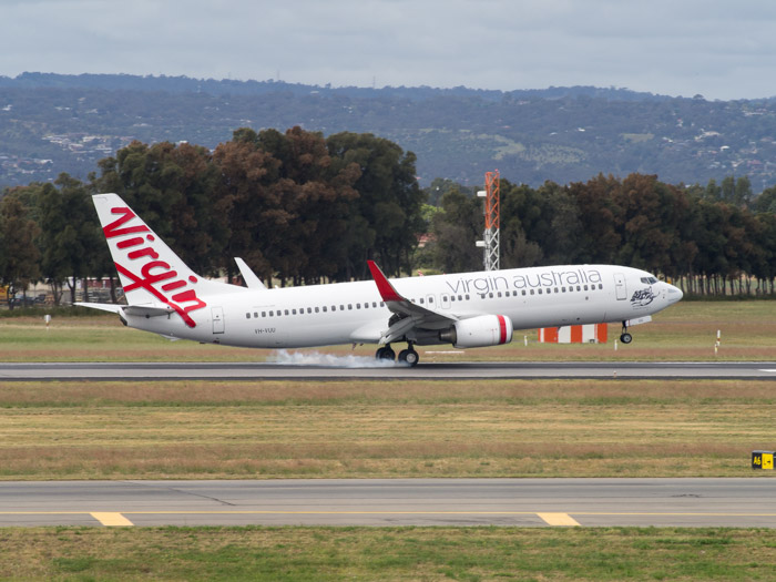 A Virgin Australian Boeing 737-8FE touching down with smoke puffs from the tires.